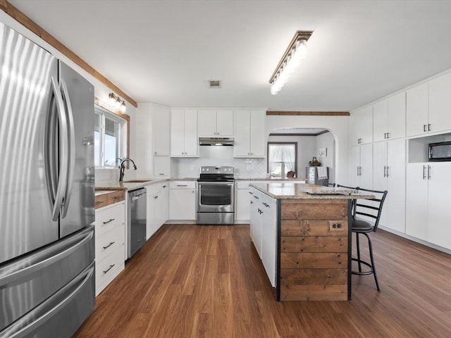 kitchen with sink, white cabinetry, stainless steel appliances, dark hardwood / wood-style floors, and a center island