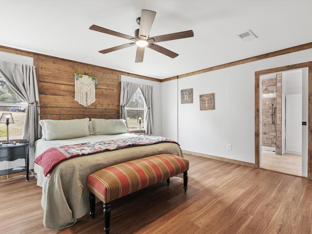 bedroom featuring ceiling fan, light wood-type flooring, and wood walls