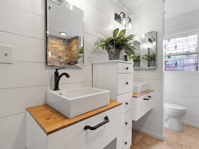 bathroom featuring tile patterned flooring, vanity, tile walls, and toilet