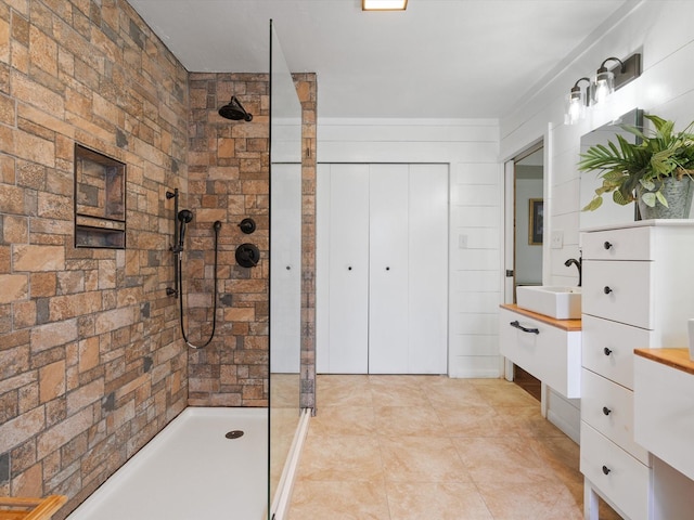 bathroom featuring vanity, tile patterned flooring, and a tile shower