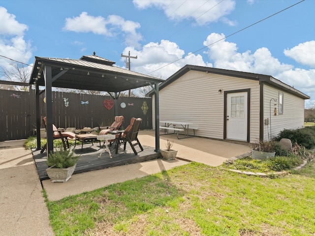 view of patio with a gazebo, an outdoor structure, a wooden deck, and a fire pit