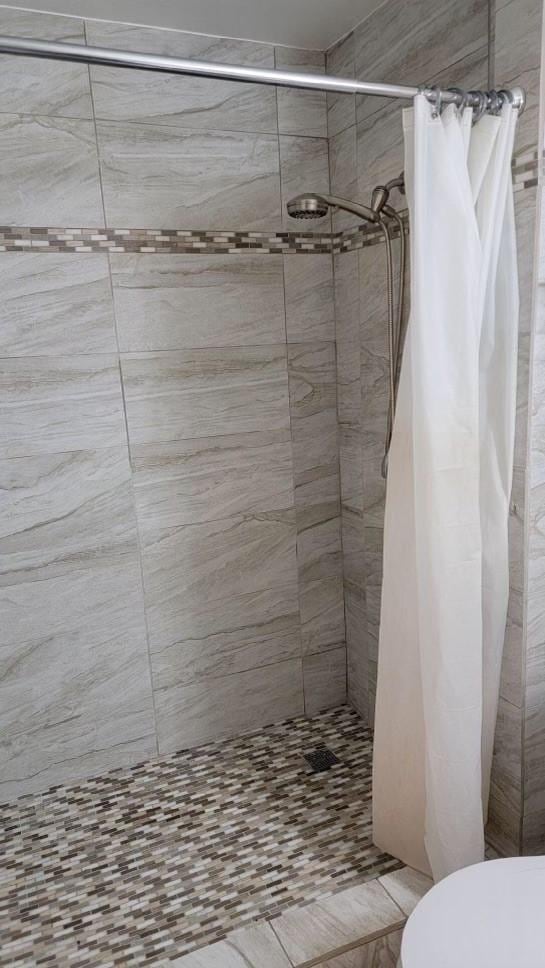 bathroom featuring toilet and curtained shower