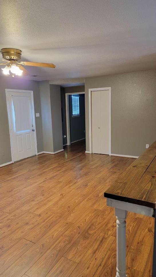 unfurnished living room with ceiling fan, light hardwood / wood-style flooring, and a textured ceiling