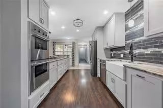 kitchen featuring white cabinetry, decorative backsplash, dark hardwood / wood-style flooring, and stainless steel appliances