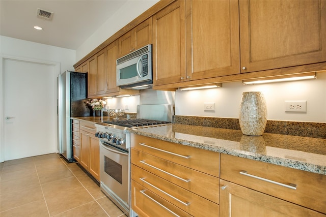 kitchen with light tile patterned flooring, stainless steel appliances, and light stone counters