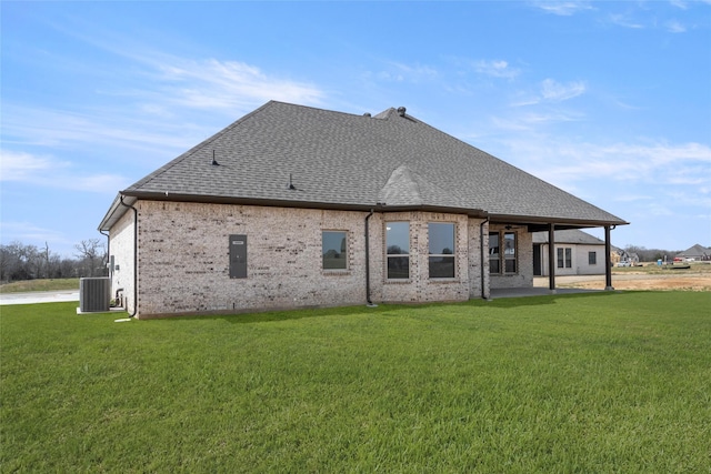 rear view of property featuring central AC, a patio, a shingled roof, and a yard