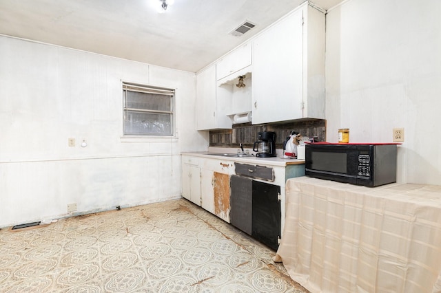 kitchen featuring visible vents, black microwave, light countertops, white cabinets, and a sink