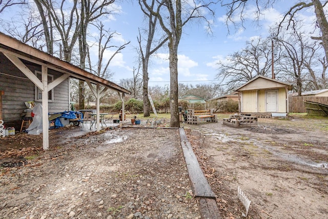 view of yard featuring an outdoor structure, a shed, and fence