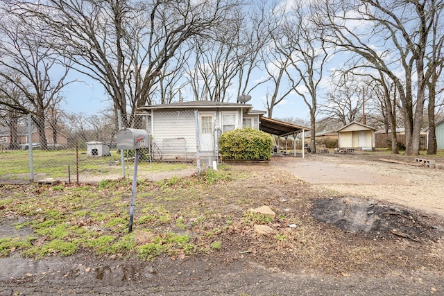 view of property exterior with an attached carport, concrete driveway, fence, and an outbuilding