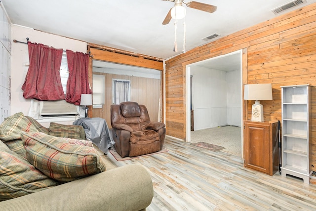 living room with visible vents, wooden walls, and wood finished floors