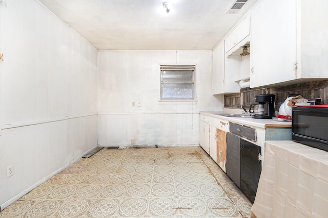 kitchen with visible vents, a sink, white cabinetry, black microwave, and light countertops