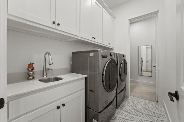 washroom featuring cabinet space, baseboards, a sink, and washing machine and clothes dryer