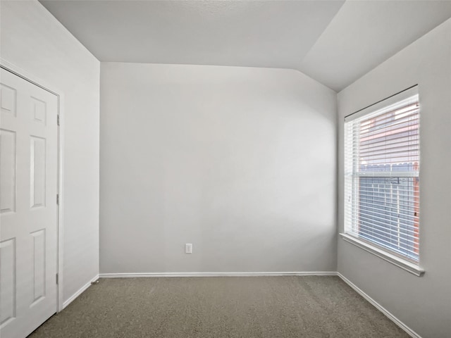 carpeted spare room with vaulted ceiling