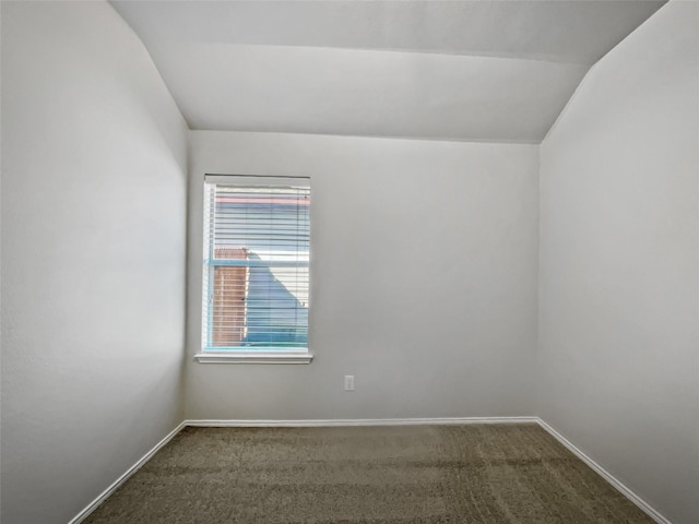 unfurnished room featuring vaulted ceiling and dark carpet