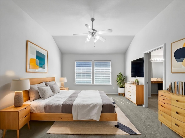 bedroom featuring lofted ceiling, ensuite bathroom, ceiling fan, and dark colored carpet