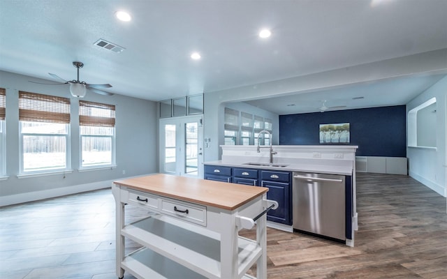 kitchen featuring visible vents, stainless steel dishwasher, blue cabinetry, white cabinetry, and a sink