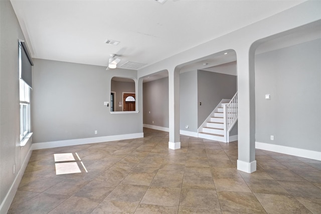 spare room with baseboards, stairs, visible vents, and arched walkways