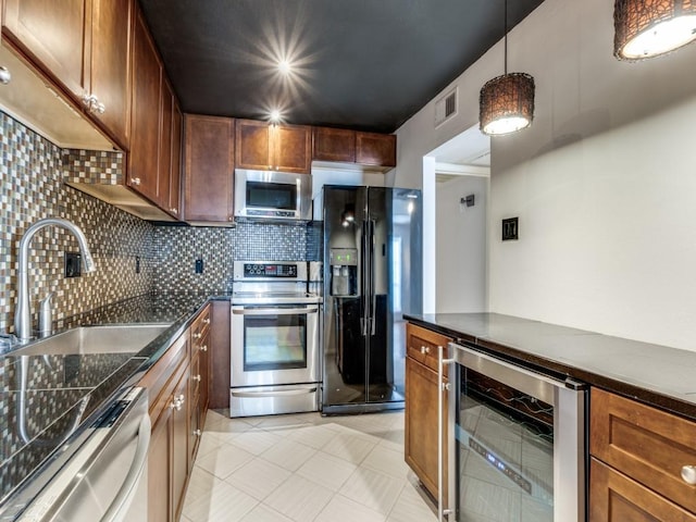 kitchen with sink, tasteful backsplash, decorative light fixtures, stainless steel appliances, and beverage cooler