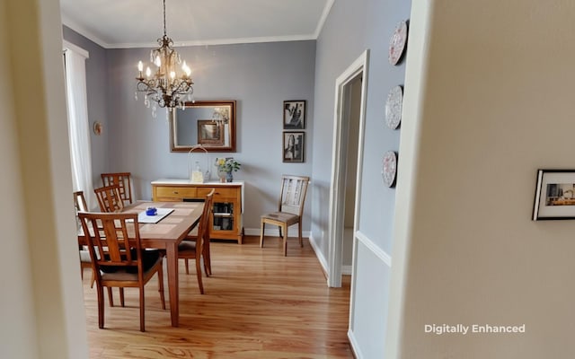 dining room featuring a notable chandelier, light wood-type flooring, and ornamental molding