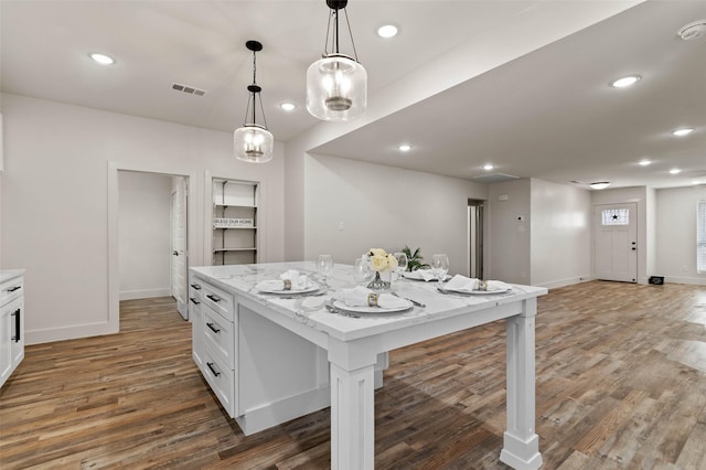 kitchen featuring white cabinetry, visible vents, light wood finished floors, and a kitchen island