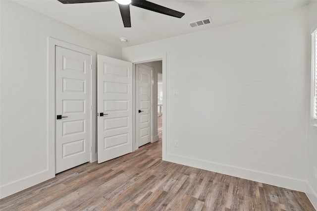 unfurnished bedroom featuring light wood-type flooring, baseboards, visible vents, and ceiling fan