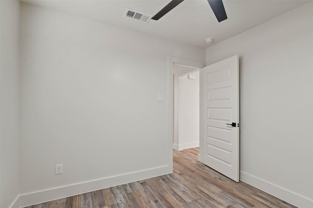 spare room featuring visible vents, ceiling fan, baseboards, and wood finished floors