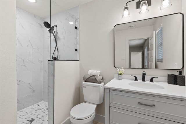 bathroom featuring a marble finish shower, toilet, vanity, and baseboards