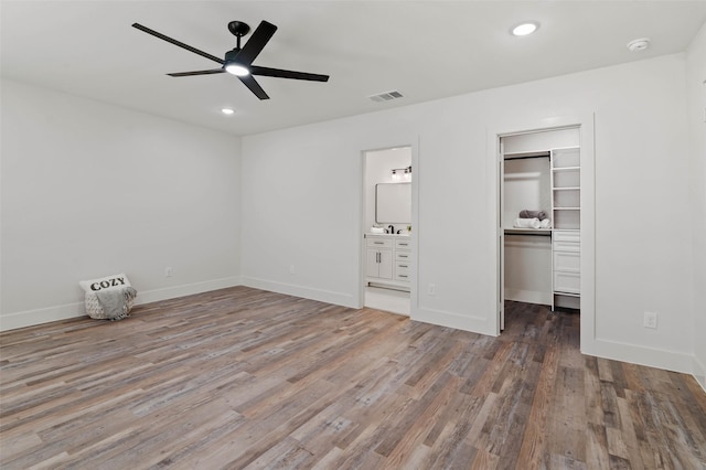 unfurnished bedroom featuring visible vents, recessed lighting, a walk in closet, and wood finished floors