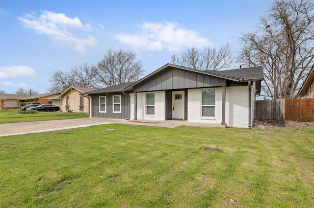 view of front of property featuring a front yard, fence, and brick siding