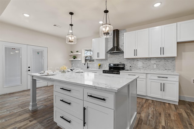 kitchen with visible vents, wall chimney range hood, decorative backsplash, stainless steel range with electric cooktop, and white cabinetry