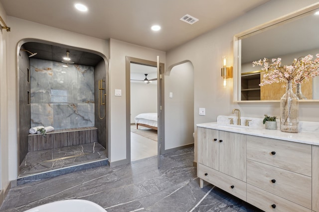 bathroom with a tile shower, vanity, and ceiling fan