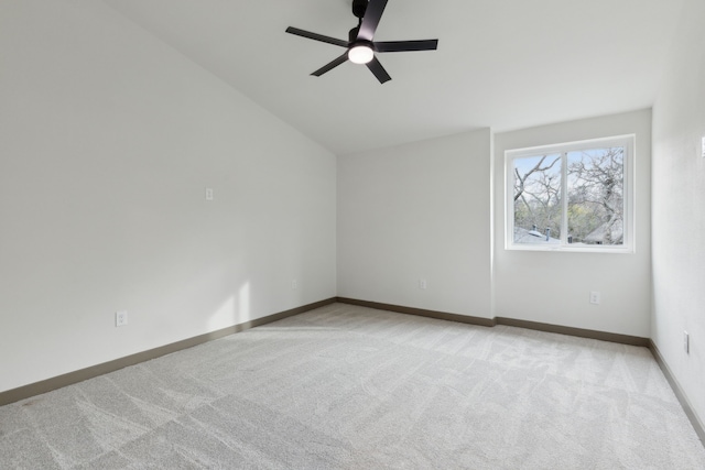 carpeted spare room featuring vaulted ceiling and ceiling fan