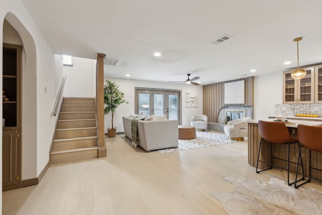 living room with ceiling fan, light hardwood / wood-style floors, and french doors