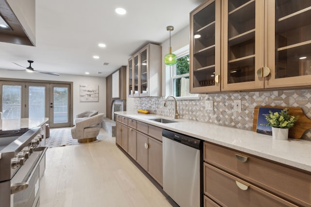 kitchen with sink, light stone counters, appliances with stainless steel finishes, pendant lighting, and backsplash