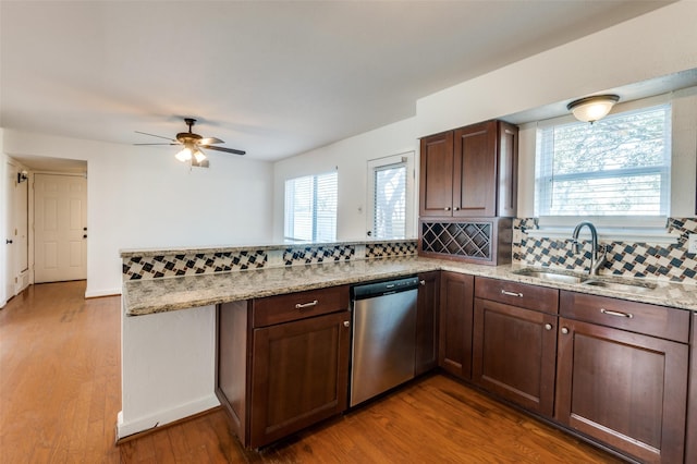 kitchen featuring tasteful backsplash, stainless steel dishwasher, kitchen peninsula, and sink