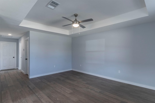 unfurnished room with a raised ceiling, dark hardwood / wood-style floors, and ceiling fan