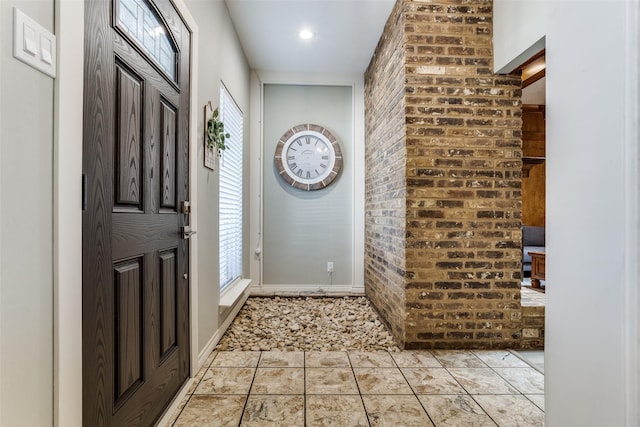 entrance foyer featuring brick wall and light tile patterned floors