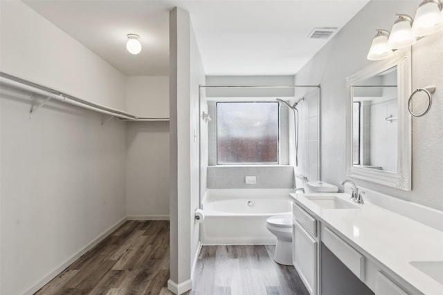 full bathroom featuring vanity, tiled shower / bath, hardwood / wood-style flooring, and toilet