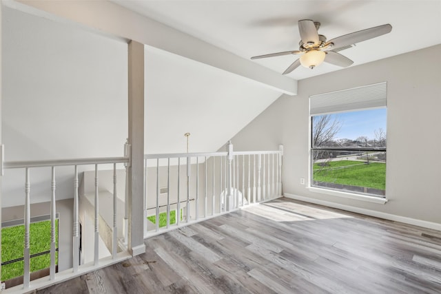 unfurnished room with hardwood / wood-style floors, lofted ceiling with beams, and ceiling fan