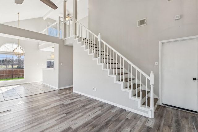 interior space with beam ceiling, hardwood / wood-style flooring, ceiling fan with notable chandelier, and high vaulted ceiling