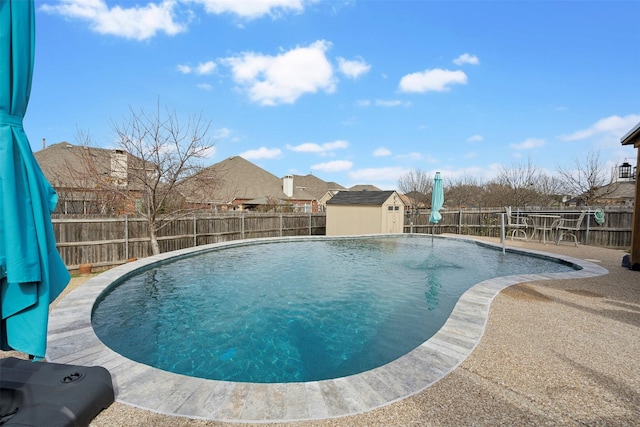 view of pool featuring an outbuilding, a fenced backyard, and a shed