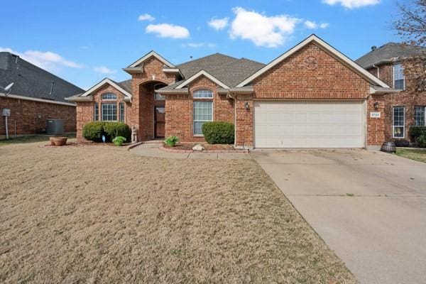 view of front of property with a garage, a front lawn, and central air condition unit