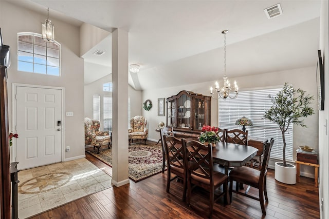 dining space featuring dark hardwood / wood-style flooring, vaulted ceiling, and a chandelier