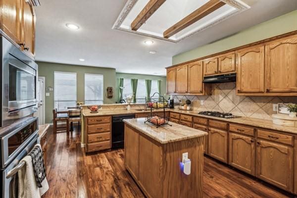 kitchen featuring a kitchen island, appliances with stainless steel finishes, backsplash, dark hardwood / wood-style flooring, and kitchen peninsula