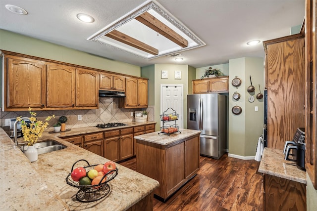 kitchen featuring sink, stainless steel fridge, backsplash, a center island, and gas stovetop