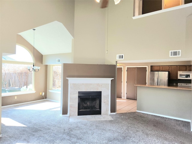 unfurnished living room featuring a high ceiling, a premium fireplace, and light colored carpet