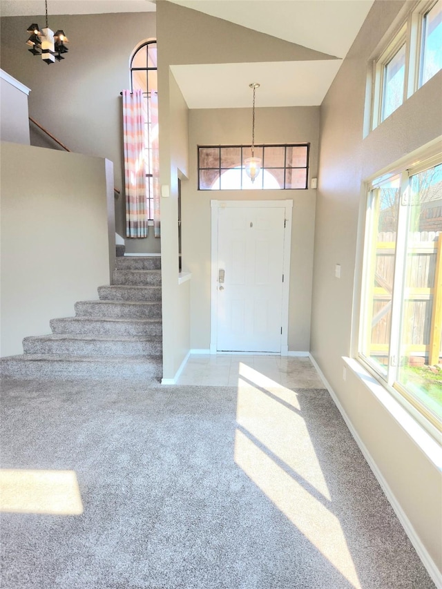 entryway featuring carpet, a chandelier, and high vaulted ceiling