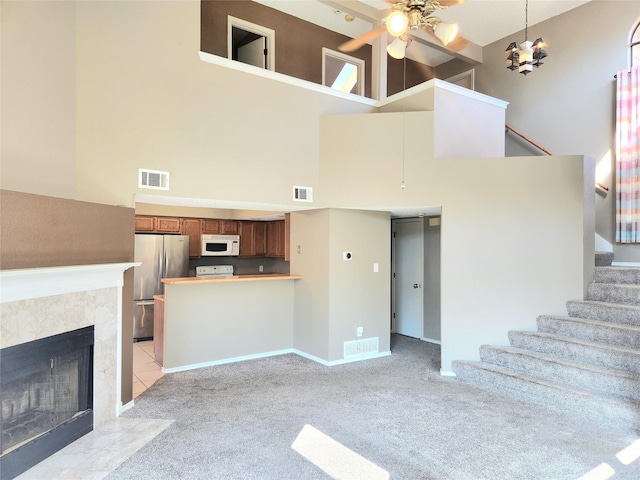 unfurnished living room featuring light carpet, a tile fireplace, and ceiling fan