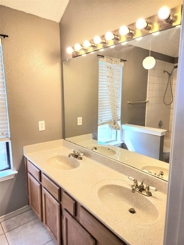 bathroom featuring tile patterned flooring, tiled shower, vanity, a textured ceiling, and toilet