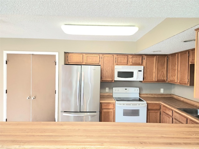 kitchen with sink, white appliances, and a textured ceiling